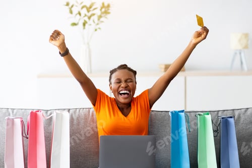 Preview: Online shopping. Afro woman with credit card and laptop buying on internet, lifting hands up