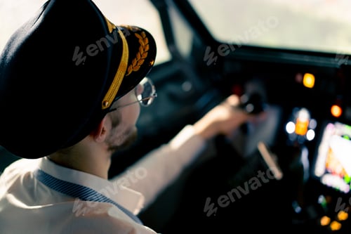 Preview: Pilot in the cockpit of an airplane holding a rotary steering wheel during flight Air travel concept