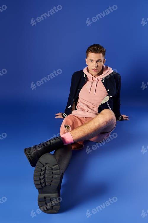 Preview: Young handsome man with prosthetic leg sitting on blue background showcasing style and confidence