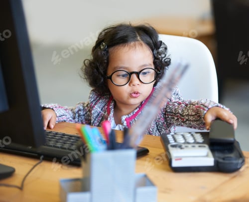 Preview: Learning as she grows. Shot of an adorable little girl playing businesswoman at a desk.