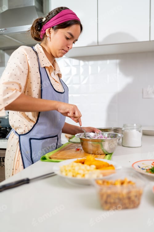 Preview: Young latin chef preparing ceviche with lime and red onion in a modern kitchen