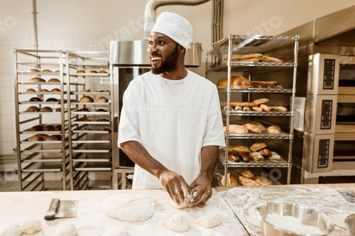 Preview: african american baker preparing raw dough for pastry on baking manufacture