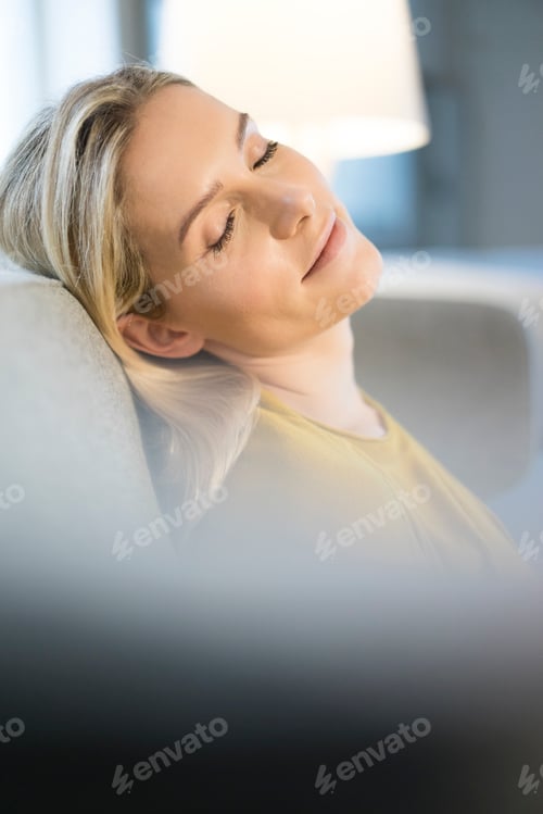 Preview: Portrait of blond woman with eyes closed relaxing on couch