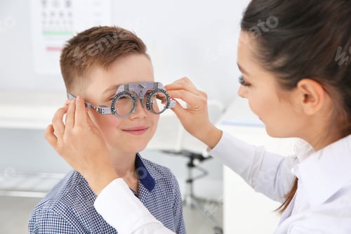 Preview: Children's doctor putting trial frame on little boy in clinic. Eye examination
