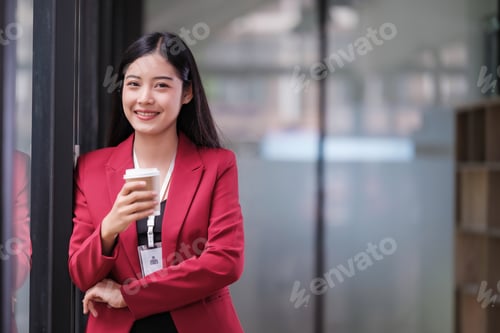Preview: Successful businesswoman smiling holding coffee cup at office. Confident business woman standing d
