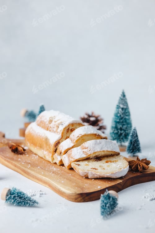 Preview: Festive sweet bread dusted with sugar on wood board with mini pine trees and pinecones