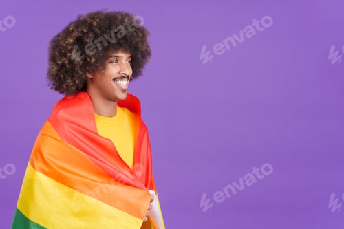 Preview: Smiling african man wrapped with a lgbt flag