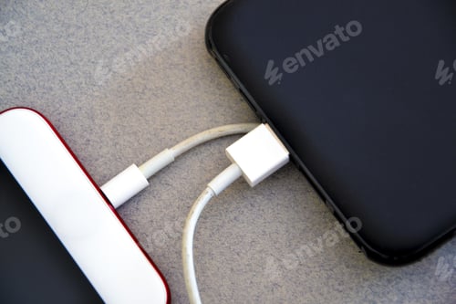 Preview: Closeup shot of a smartphone connected to a power bank on a gray surface