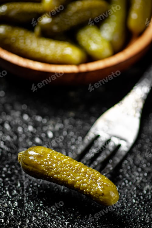 Preview: Wooden plate with pickles. On a black background.