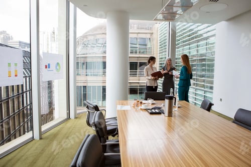 Preview: Colleagues discussing over documents in a welllit office conference room.