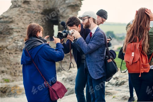 Preview: Men photographing woman holding smart phone at beach