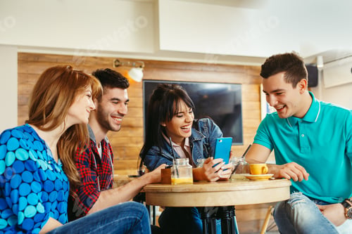 Vista previa: Grupo de jóvenes divirtiéndose en la cafetería a través de un teléfono inteligente