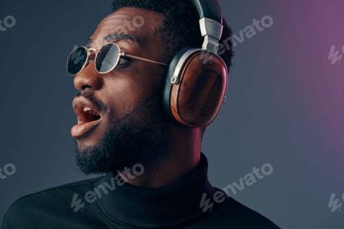 Young African man wearing stylish headphones and sunglasses, enjoying music with a vibrant