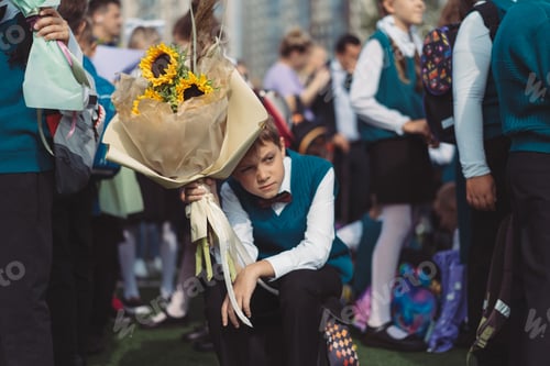 Preview: A 10-year-old boy carries a bouquet of flowers stressed before school on September 1st, dressed in formal attire with a backpack.