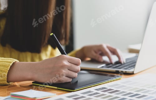 Preview: Woman writing on a digital board with a pen and working on a laptop.