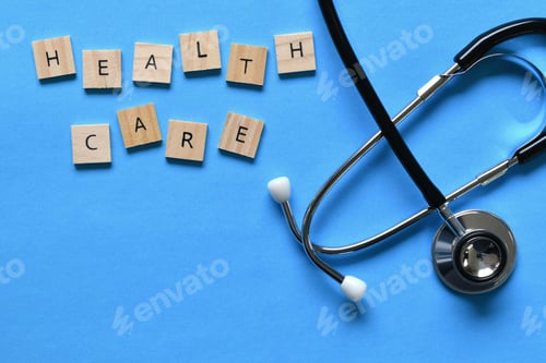 Preview: Overhead flat lay of a stethoscope on a light blue background with the words HEALTH CARE spelled out