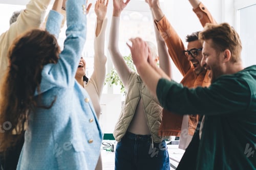 Preview: Group of diverse colleagues standing with raised hands in office