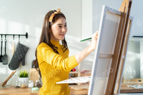 Preview: Asian young talented woman artist coloring on painting board in house.