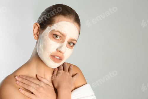 Preview: Beautiful woman with clay mask on her face against grey background. Space for text