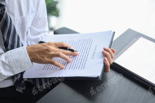Preview: Male executive singing legal documents for a corporate partnership at desk.