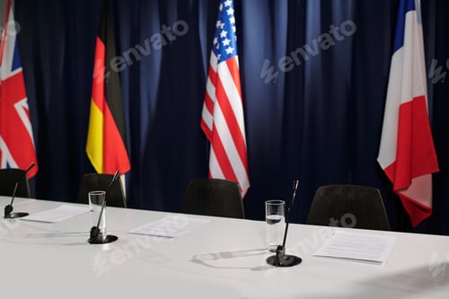 Preview: Row of microphones and glasses of water prepared for participants of summit
