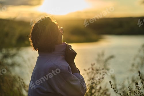 Preview: thoughtful, modern retiree immerses herself in tranquility of summer meadow, wildflowers in her