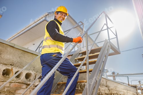 Preview: Cheerful male engineer climbing stairs at factory
