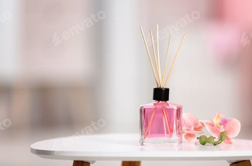 Preview: Aromatic reed air freshener and flowers on table against blurred background