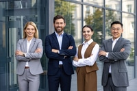 Preview: Four confident employees wearing business clothes and smiling widely to camera with arms folded on