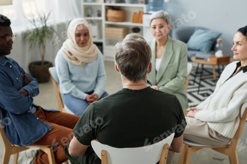Preview: Focus on rear view of mature male patient of counselor sitting in front of group
