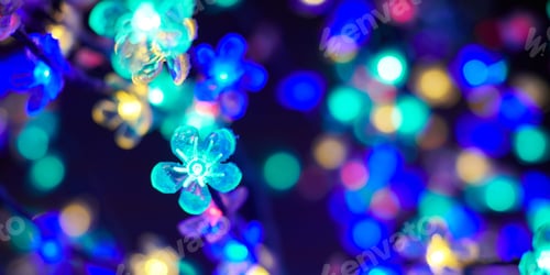 Preview: Multicolored lights bokeh from decorative luminous flowers garlands at holiday, multicolored lights