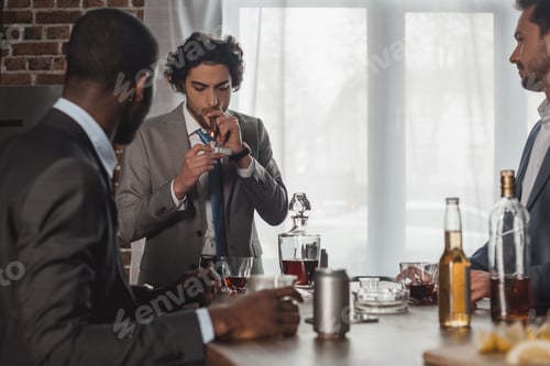 Preview: cropped shot of multiethnic men drinking alcohol and looking at friend smoking cigar