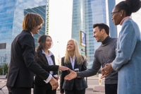 Preview: Group of multi-ethnic business people in a business park introducing themselves and shaking hands