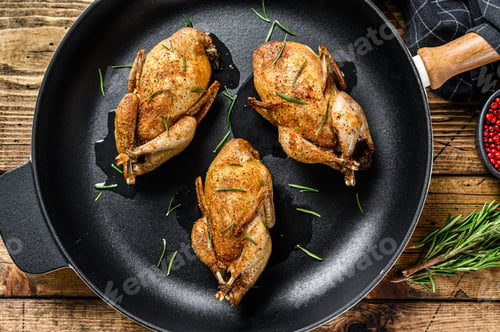 Preview: Homemade roast quail in a pan. Wooden background. Top view