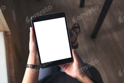 Preview: a woman sitting cross legged and holding black tablet pc with blank white desktop screen