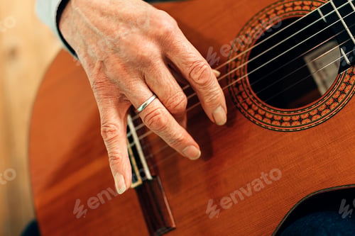 Preview: close up on the hands of an old guitarist playing acoustic guitar