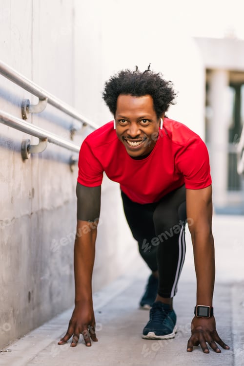 Preview: Athlete man in start position preparing to run outdoors.