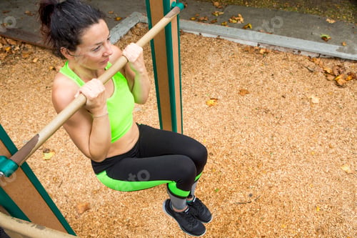 Preview: Woman focused on her outdoor workout on pullup bars