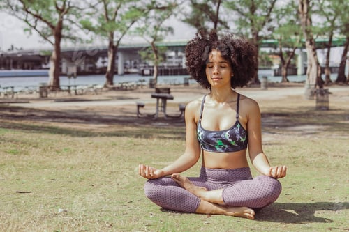 Preview: Content woman meditating in sunlight in park