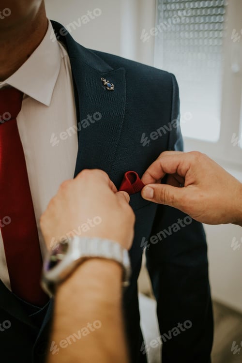 Preview: Vertical shot of a man's hands fixing the handkerchief of a groom