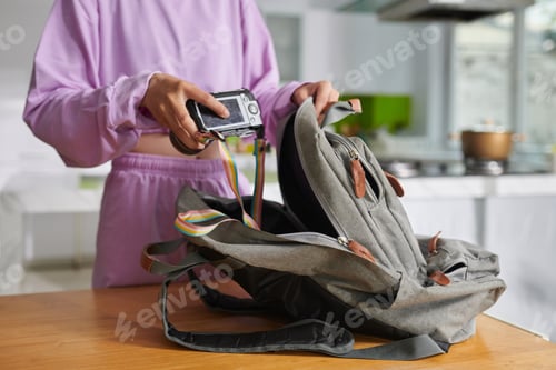 Preview: Girl Putting Camera in Backpack