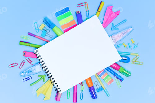 Preview: A set of multi-colored school and office stationery laid out under a blank sheet of notebook.