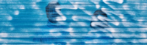 Preview: couple in warm outfit behind blue frozen plastic sheet in studio, winter concept, horizontal banner