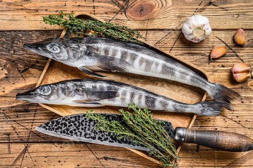 Preview: Raw mackerel icefish in a wooden tray. Wooden background. Top view