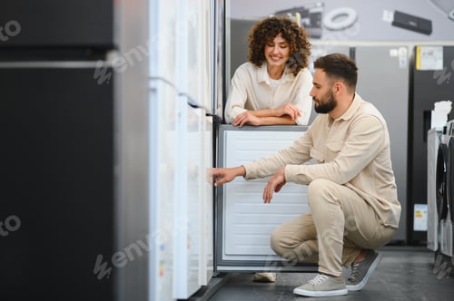 Preview: Couple choosing refrigerator in electronics store examining home appliances