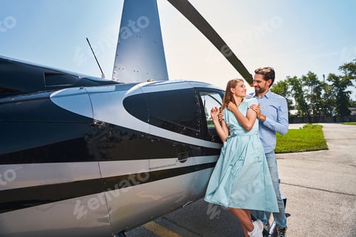 Preview: Loving couple standing by private helicopter outside