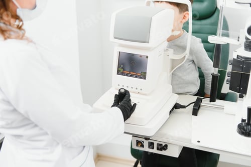 Preview: Close up of ophthalmologist using auto refractometer while examining child eyes.