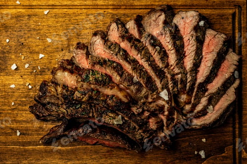 Preview: Close-up of sliced boneless ribeye steak served on a wooden board in a restaurant