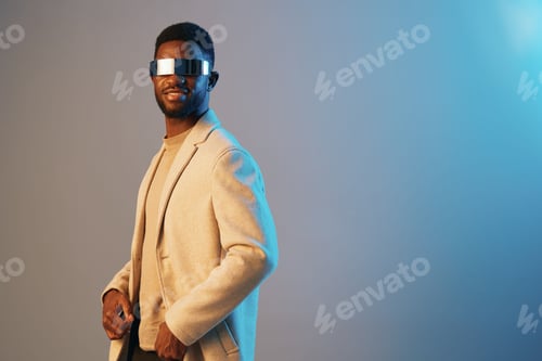 Preview: Stylish black man wearing futuristic sunglasses and a blazer, exuding confidence against a cool