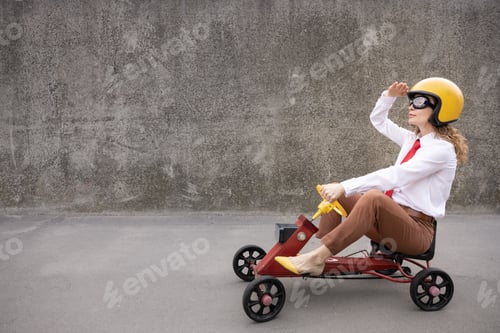 Preview: Funny businesswoman driving retro pedal car outdoor